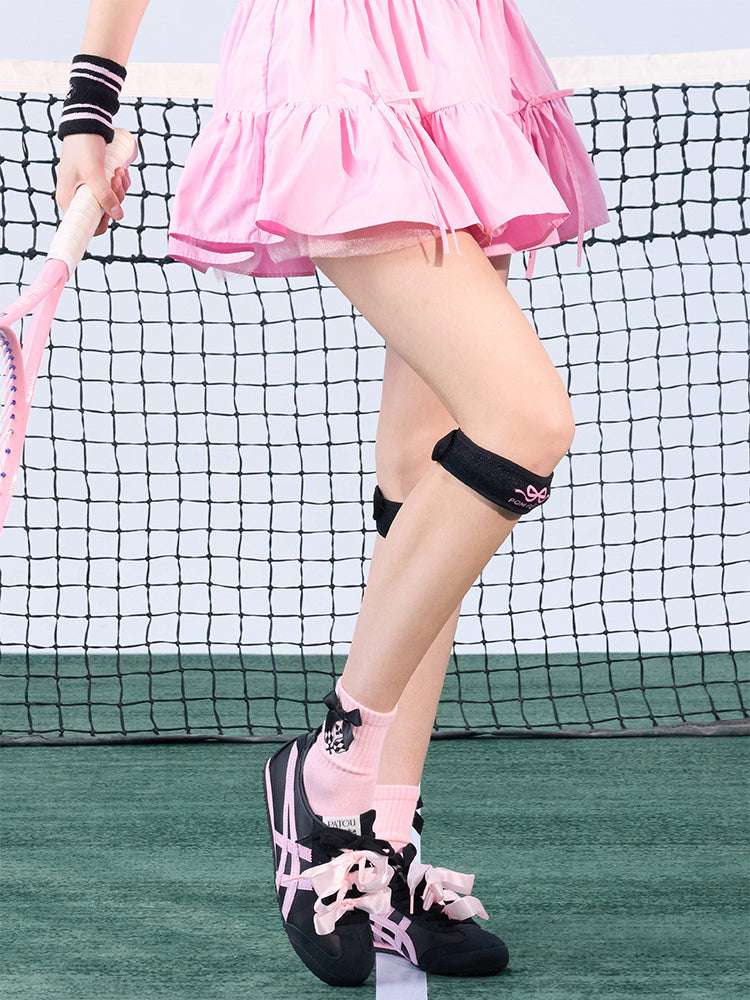 Tennis look featuring a black patella support strap with bow print. 