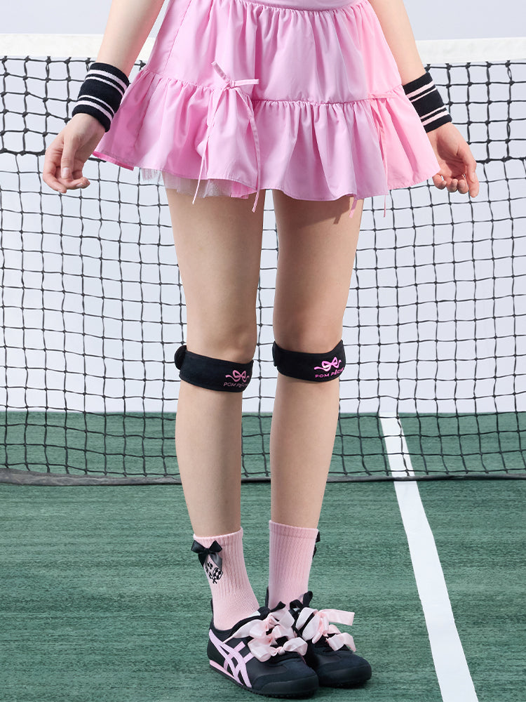 Tennis look featuring a black patella support strap with bow print. 