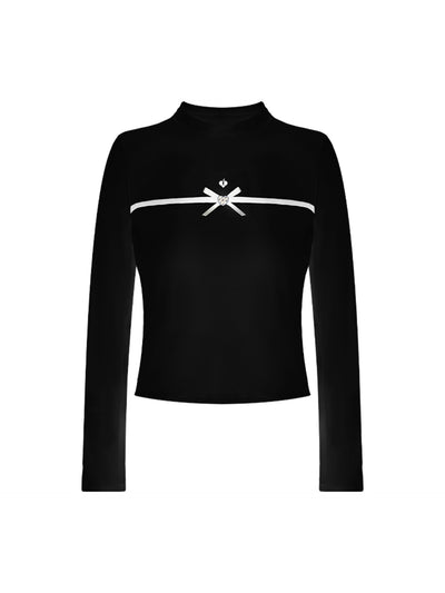 Black long-sleeve top with a smooth silhouette and contrast bow detail, styled on the tennis court.