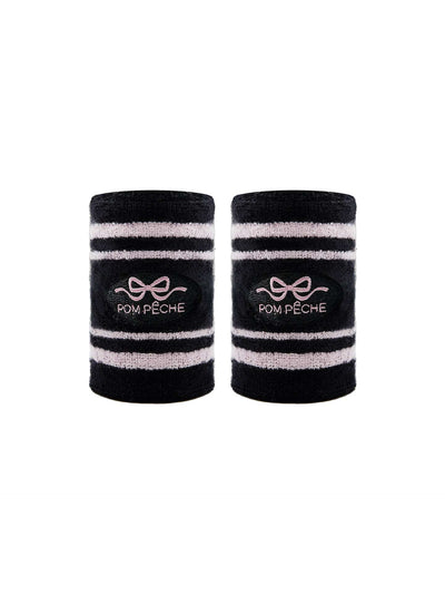 Black tennis wristbands with soft pink stripes, featuring embroidered bow and logo details.