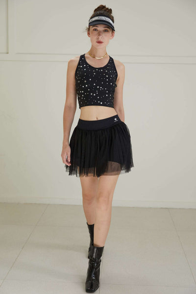 Model walking in black puff tulle tennis skirt and boots, highlighting airy mesh movement and a high-waisted athletic tennis skirt fit.