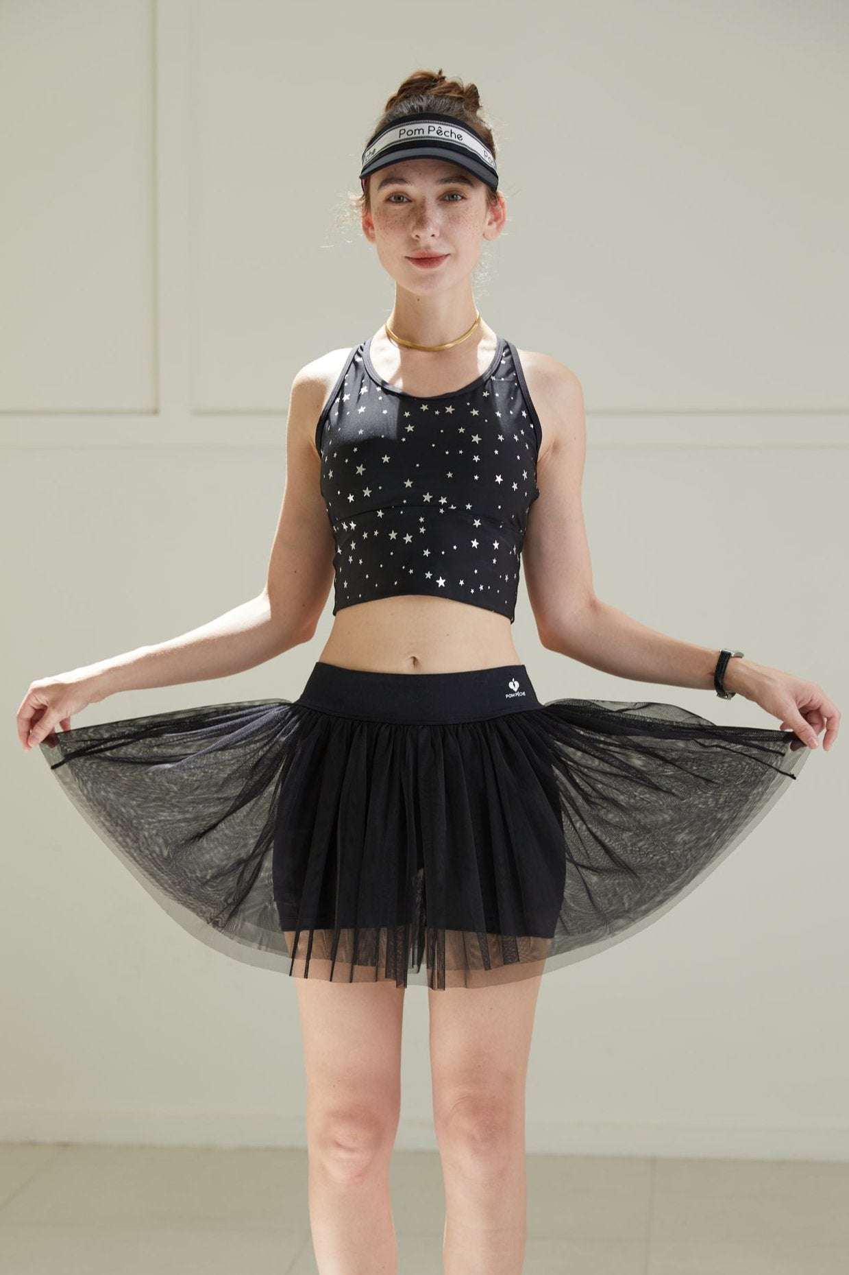 Front view of black tulle puff tennis skirt lifted to show mesh layers, emphasizing lightweight volume and high-waisted athletic silhouette.