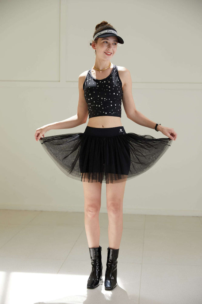 Model posing in black puff tulle tennis skirt indoors, highlighting airy mesh texture and a refined high-waisted athletic tennis skirt design.