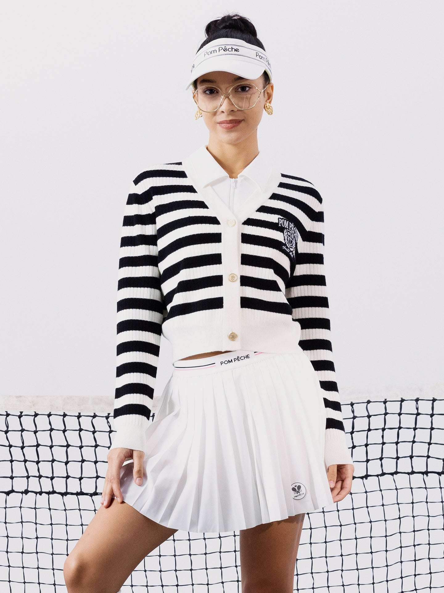 Black and white striped cardigan with a V-neck, button-down design, featuring an embroidered logo. Styled from court to café.