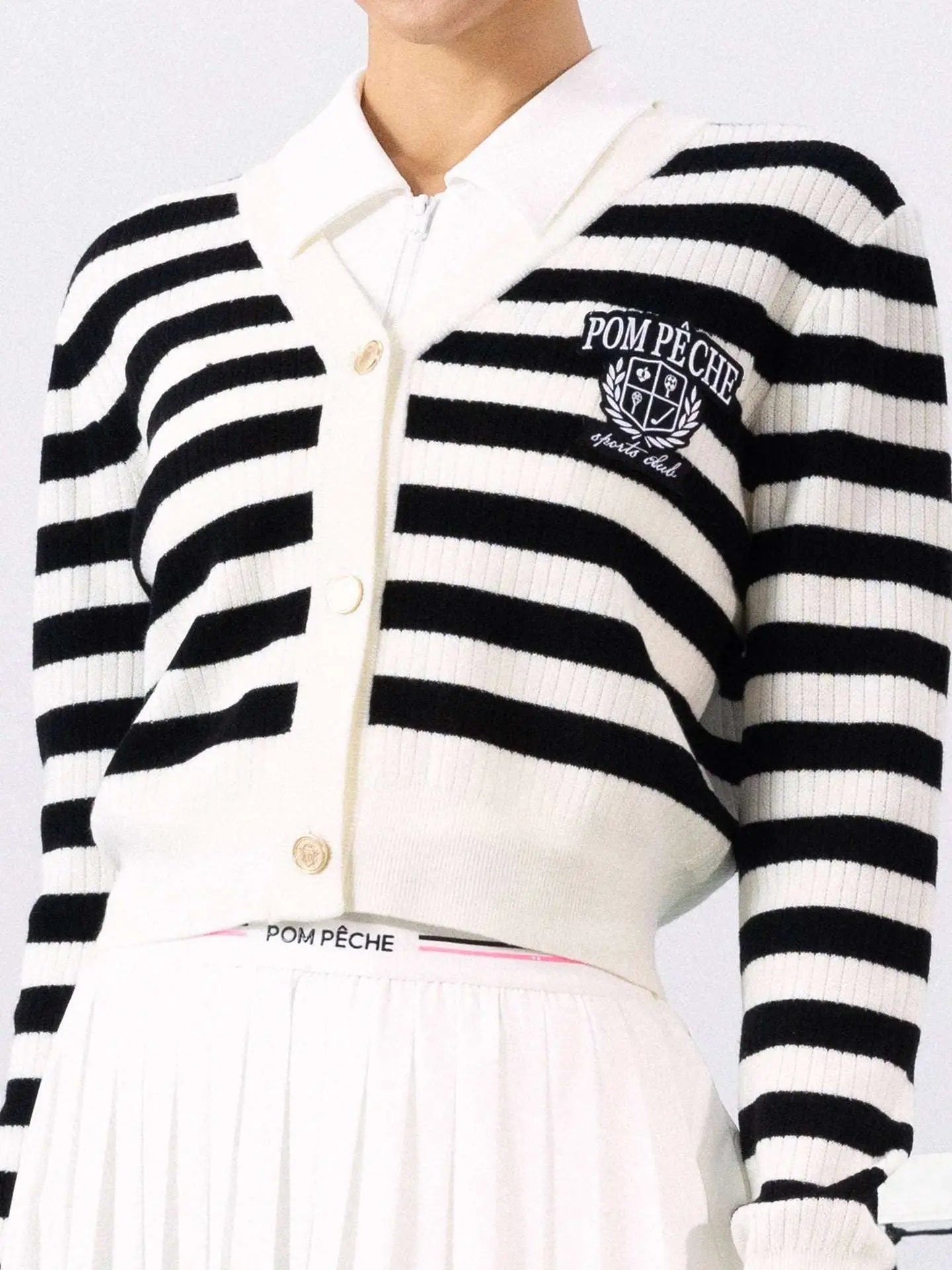 Model playin tennis wearing Pom Peche cardigan. 