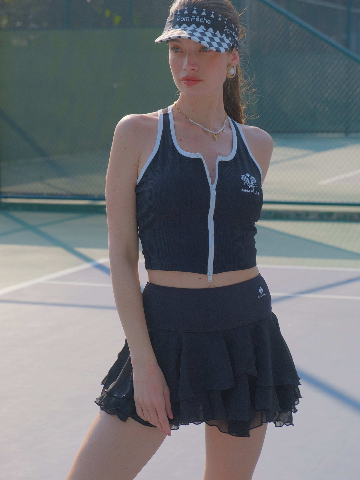 Black cropped zip-front tank top with contrast trim and subtle logo, designed for a sleek, sporty look on the court.