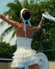 Light blue halter neck crop top with bow detail and subtle logo, styled on the tennis court.
