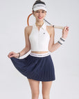 A model is wearing a blue navy pleated tennis skirt styled for athletic performance on court
