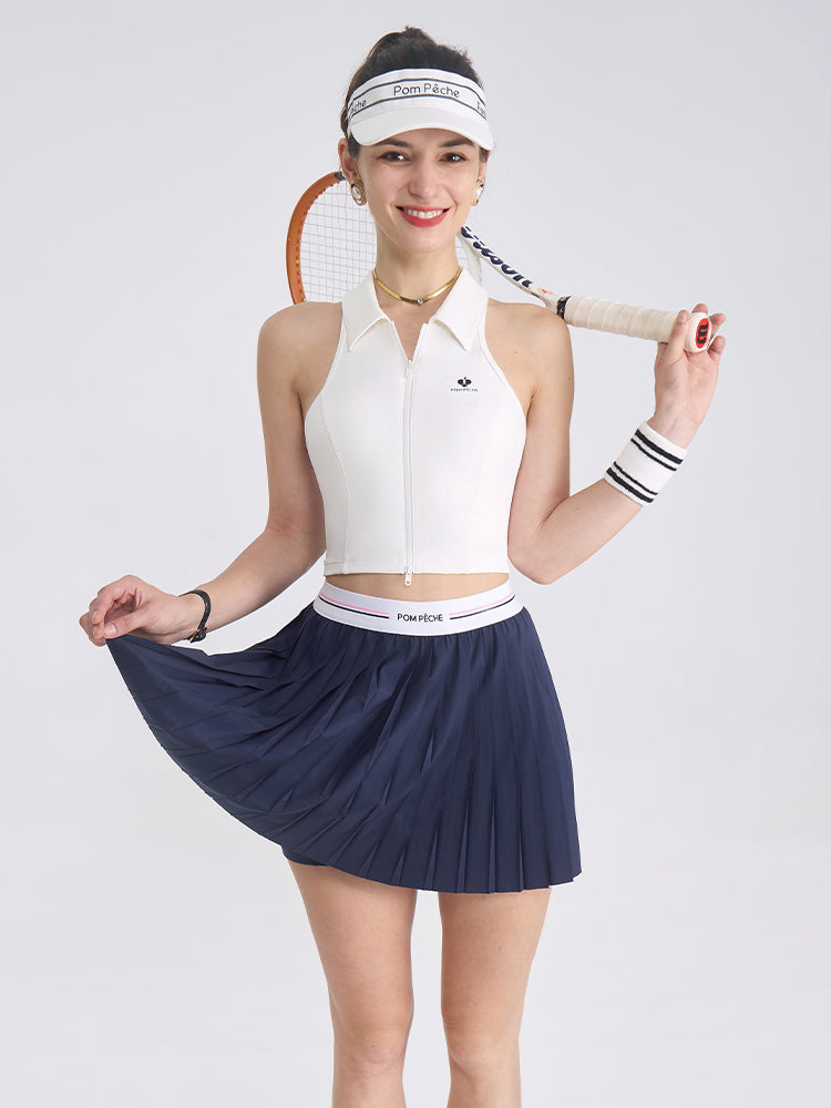 A model is wearing a blue navy pleated tennis skirt styled for athletic performance on court