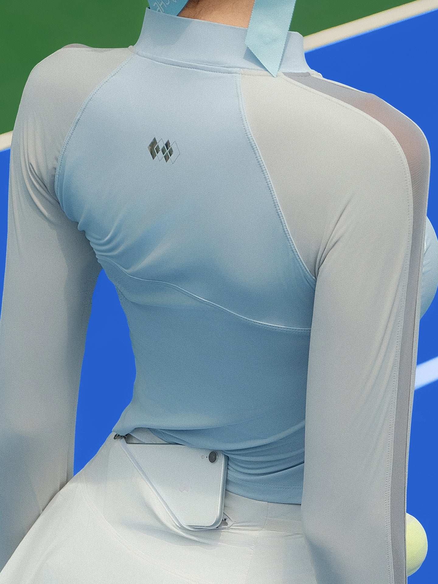 Sky blue long-sleeve fitted top with a half-zip neckline and subtle logo detail, styled on the tennis court.