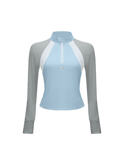 Sky blue long-sleeve fitted top with a half-zip neckline and subtle logo detail, styled on the tennis court.