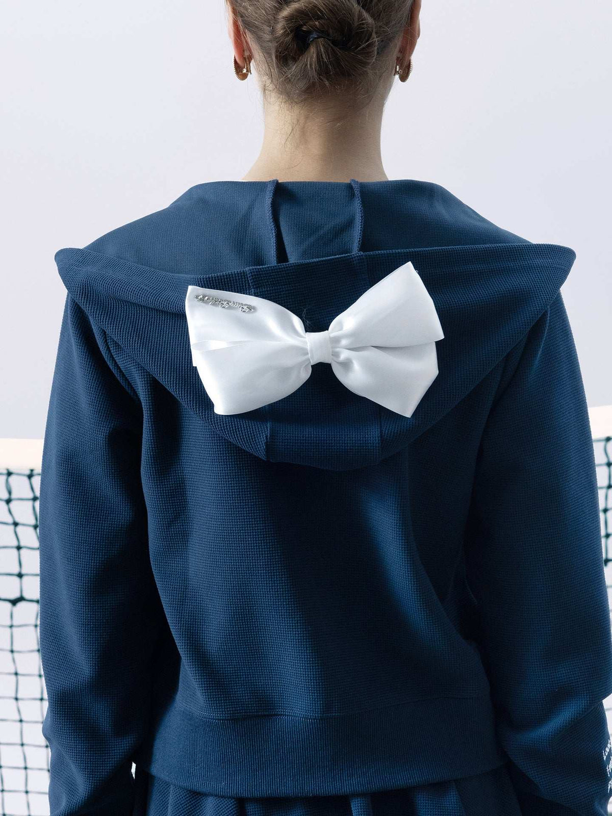 Navy blue zip-up hoodie with bow detail on the hood and embroidered logo, perfect for warm-ups or everyday wear.