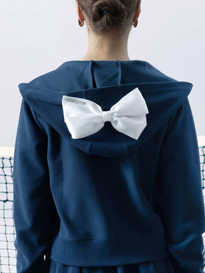 Navy blue zip-up hoodie with bow detail on the hood and embroidered logo, perfect for warm-ups or everyday wear.