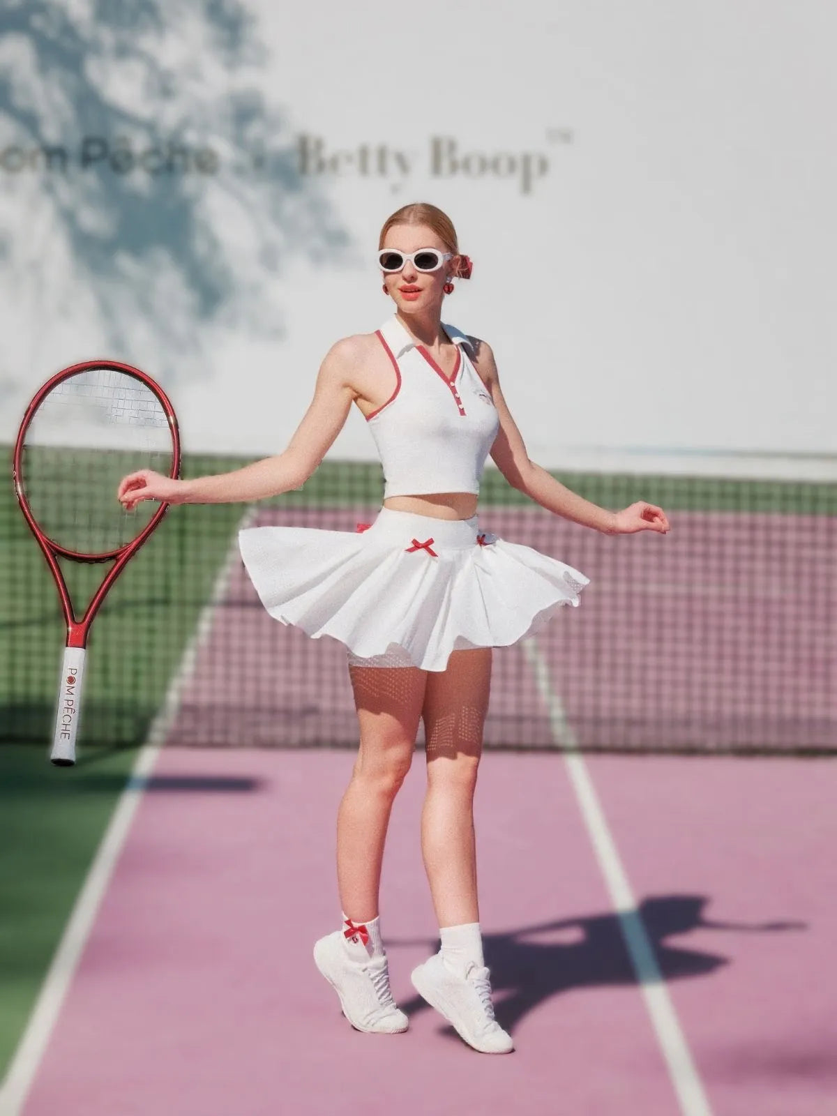 Woman in a tennis outfit with a skirt and top on a tennis court, holding a racket.