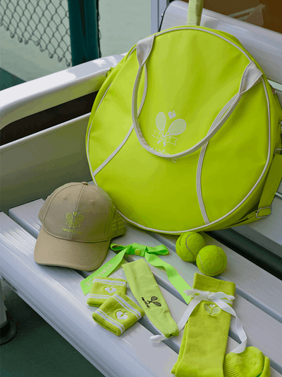 Green round tennis bag with white trim and handles, featuring Pom Pêche logo.