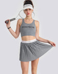A women’s grey pleated tennis skirt designed for lightweight movement and court performance, styled with a sporty elastic waistband.