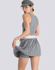 A grey women’s pleated tennis skirt with built-in shorts and a flexible waistband, offering comfort and style for active sports.