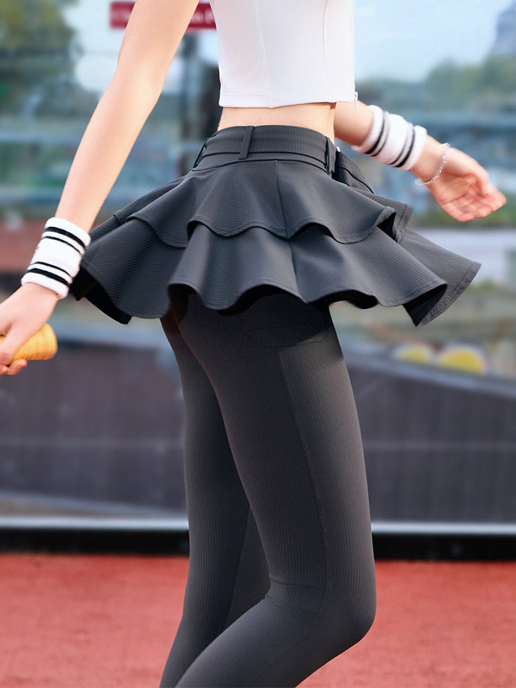Grey tennis leggings with a tiered ruffle skirt and high waist, stretchy fabric for comfort and active movement .