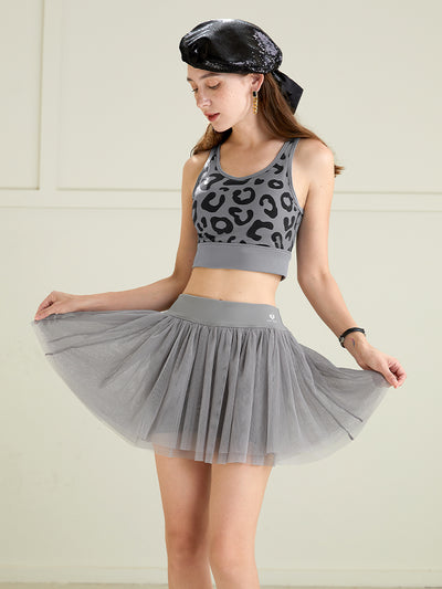 Model styling a grey tulle puff tennis skirt with printed top, emphasizing soft layered mesh and high-waisted athletic tennis skirt shape.