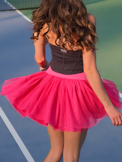 Back view of hot red tulle puff tennis skirt spinning on court, emphasizing lightweight mesh and high-waisted athletic tennis skirt silhouette.