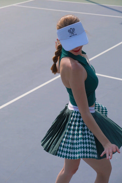 Person wearing a green tennis outfit with a visor on a tennis court