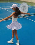 Woman in tennis attire on a blue tennis court with a club logo in the background