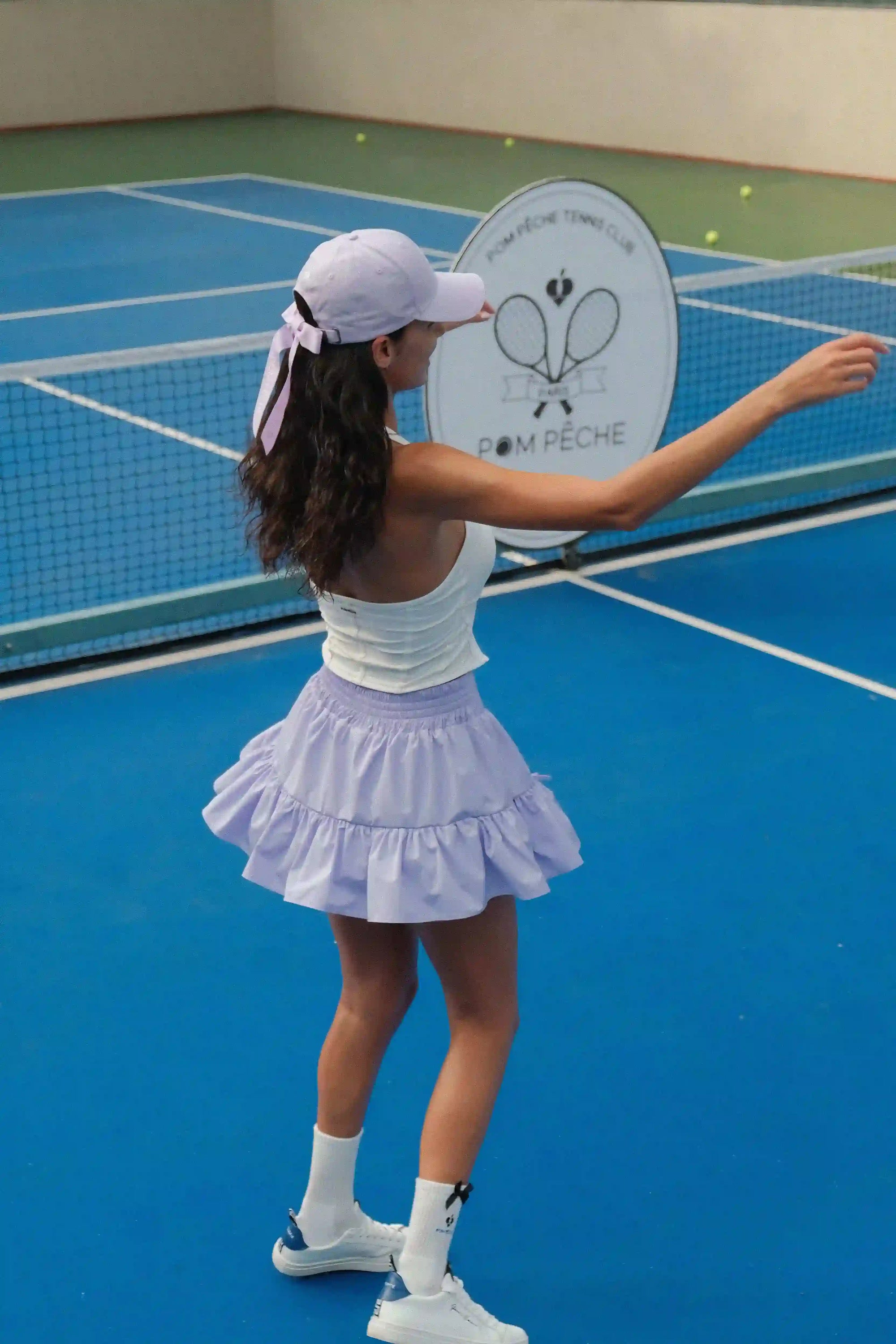 Person in tennis attire on a court with a racket