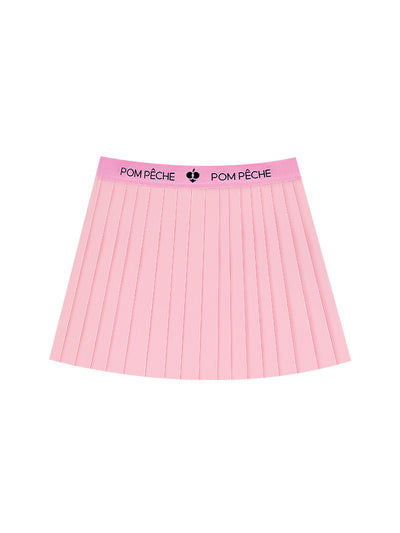 A sporty outfit features a light pink pleated tennis skirt designed for women’s tennis, pickleball and activewear looks.