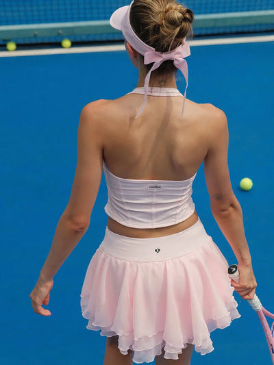 Tennis player in a white top and pink skirt on a blue tennis court.