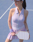 Woman in a lavender tennis outfit holding a racket on a tennis court