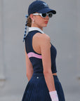 Back view of navy blue short pleated tennis skirt with smooth waistband and uniform pleats falling from the hip.