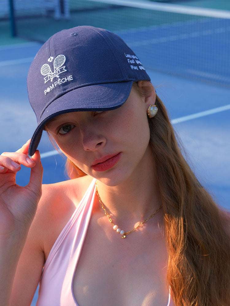 Navy blue tennis baseball cap with embroidered Pom Pêche logo and detachable ribbon.