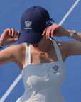 Navy blue tennis baseball cap with embroidered Pom Pêche logo and detachable ribbon.