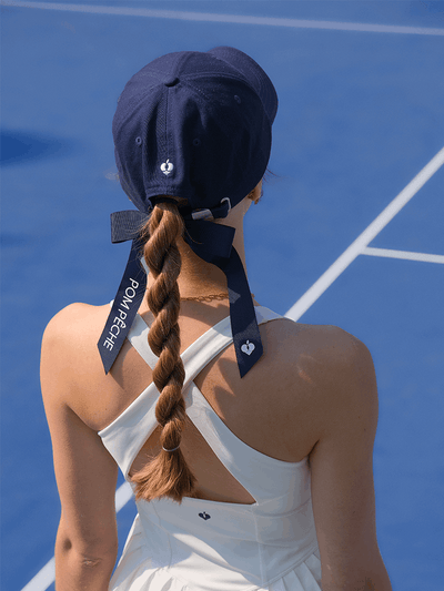 Navy blue tennis baseball cap with embroidered Pom Pêche logo and detachable ribbon.