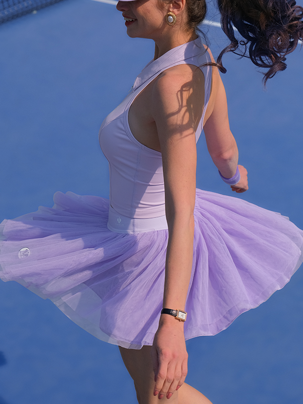 Lavender tulle puff tennis skirt flowing in motion on court, highlighting airy layered mesh and a high-waisted athletic tennis skirt silhouette.