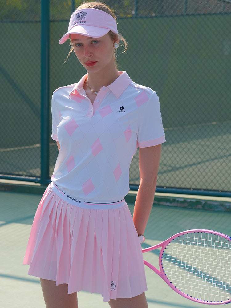 White and pink checkered polo top with diamond pattern and subtle logo, styled on the tennis court.