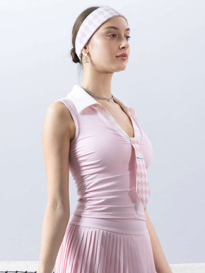 Soft pink slim-fit tennis top with a playful diamond-pattern tie detail, styled for a chic on-court look.