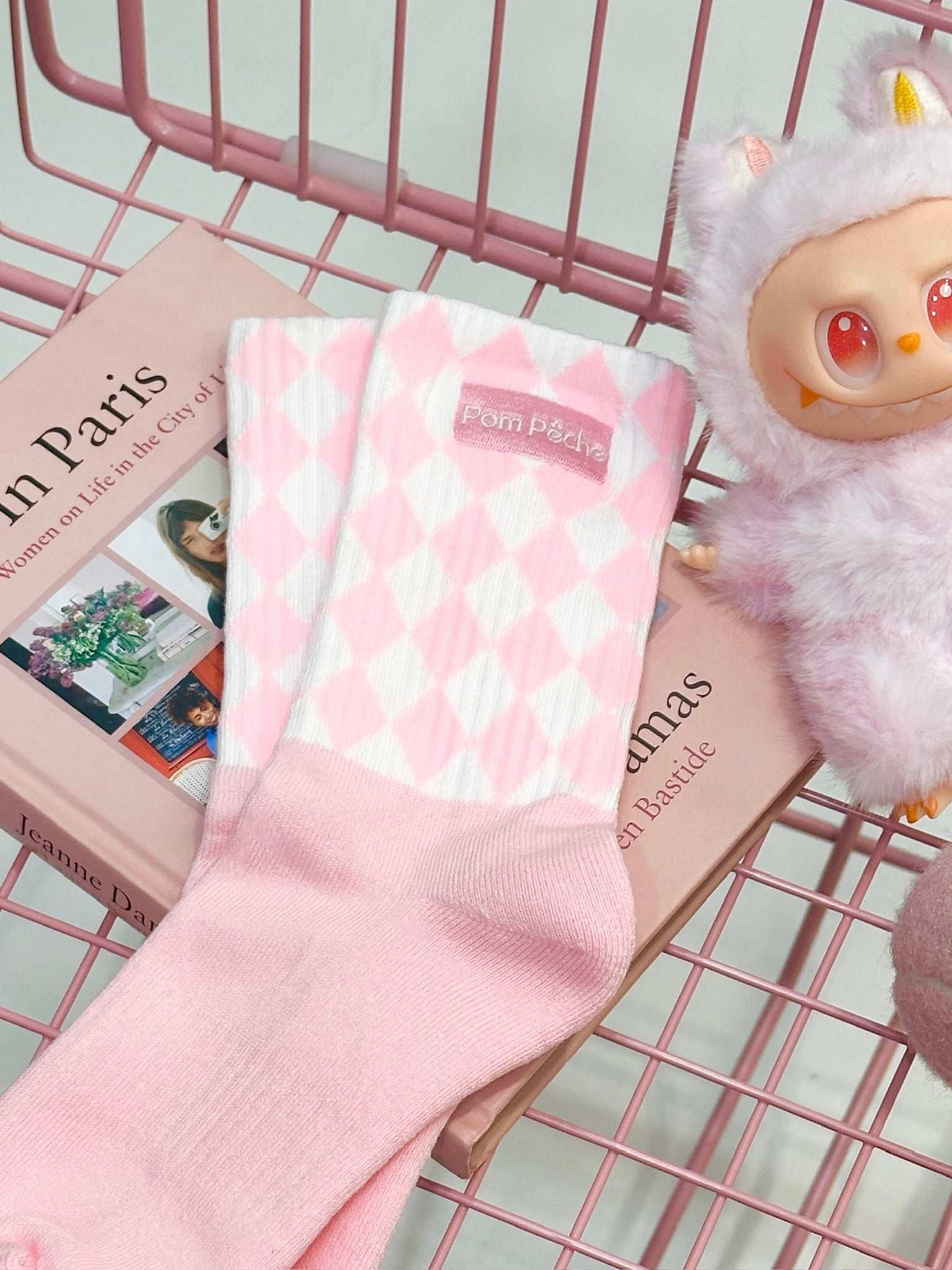 Pink mid-crew socks with checkered pattern and Pom Pêche logo, styled with a soft, casual aesthetic.