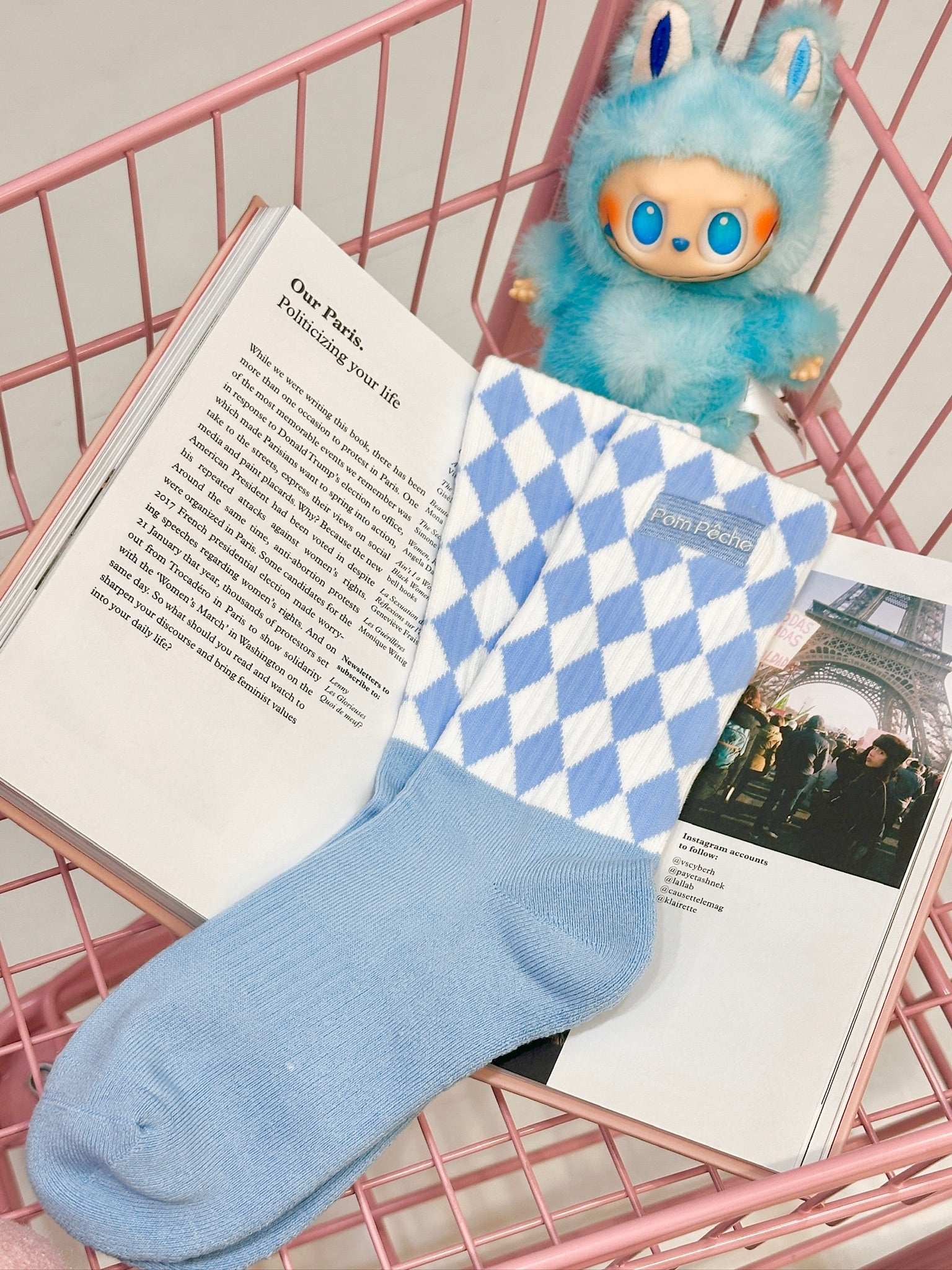 Sky blue mid-crew socks with checkered pattern and Pom Pêche logo, styled with a soft, casual aesthetic.