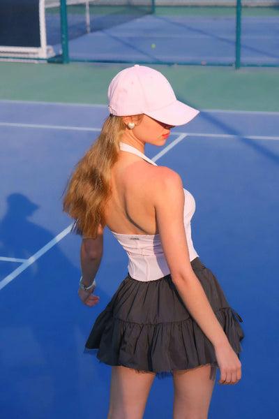 Woman in a white top and black skirt on a tennis court