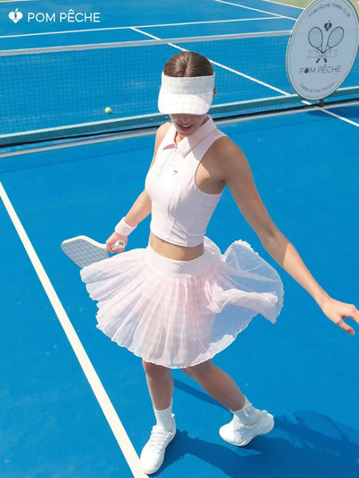 Soft pink half-zip cropped tennis polo top with breathable mesh back and printed logo, designed for lightweight comfort on court.