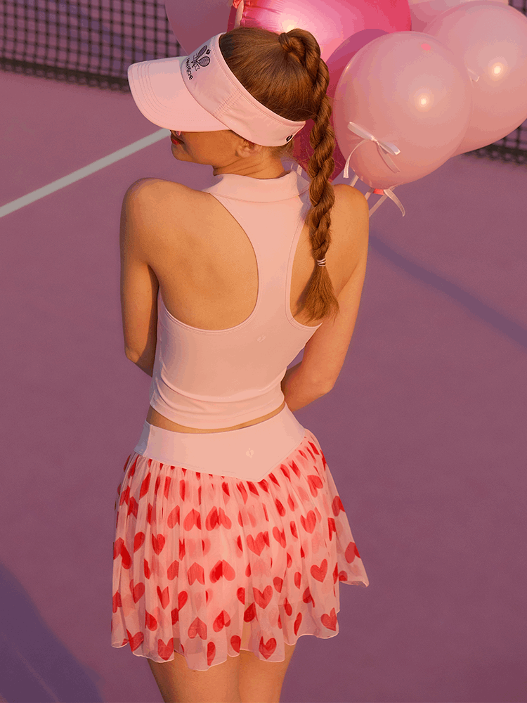 Back view of the Mesh Tennis Skirt - Pink Heart showing the flared silhouette and soft pleated mesh while the model holds balloons