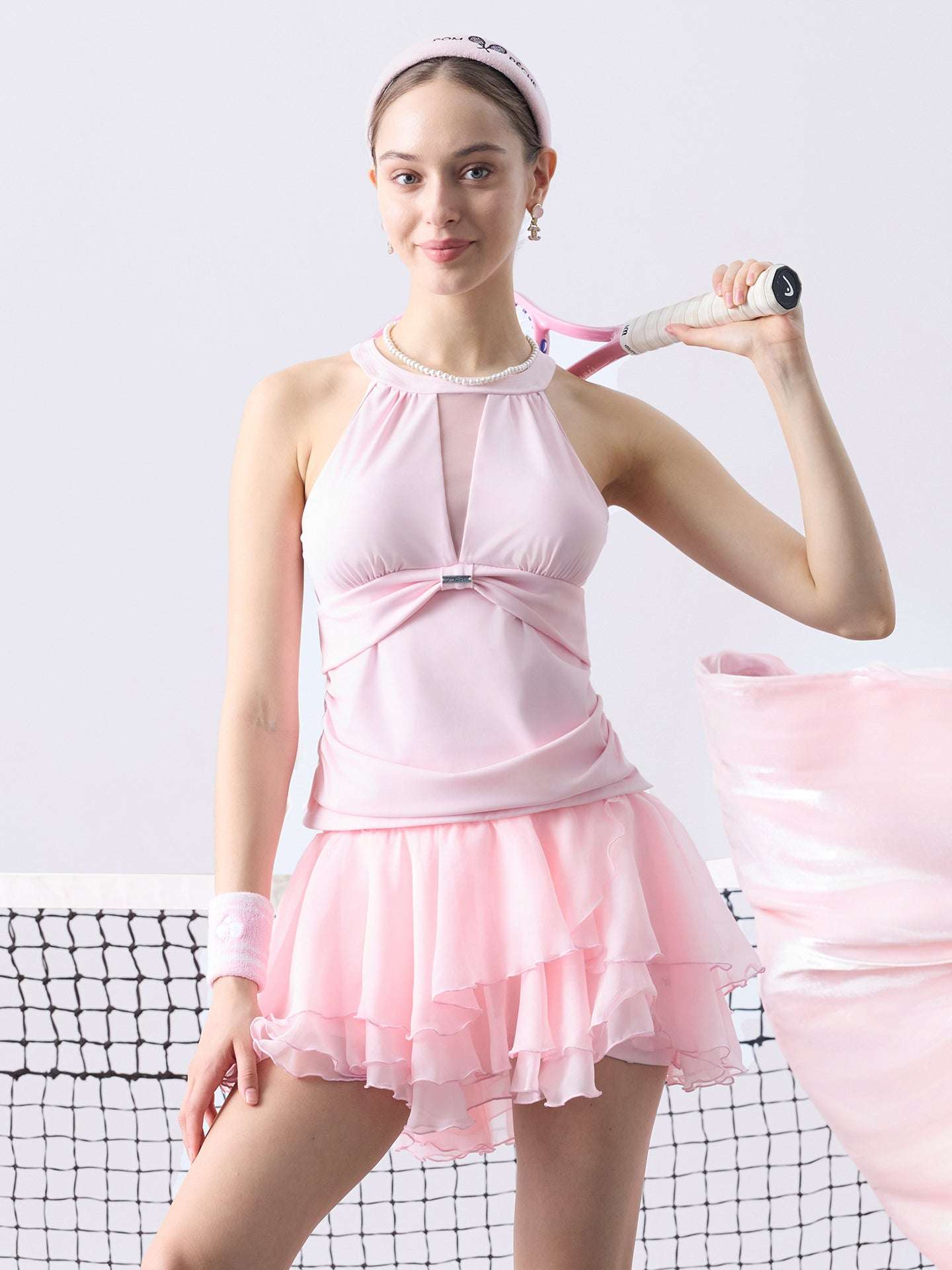 Soft pink mesh halter tennis top with a twist-front detail, offering a flattering fit and lightweight comfort for on-court wear.