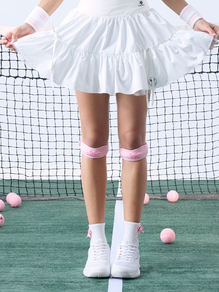 Tennis look featuring a pink patella support with a bow detail.