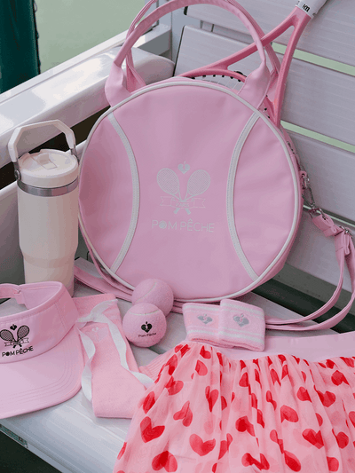 Pink round tennis bag with handles, featuring brand logo and racket-shaped zipper.