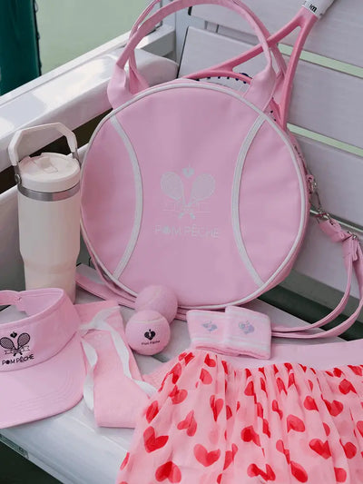 Pink sports bag, hat, towel, and other accessories on a white surface.