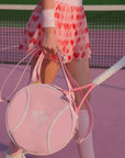 Person holding a pink tennis racket and bag on a tennis court