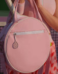 Pink tennis bag with a racket charm held by a person wearing a pink outfit.