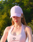 Woman wearing a pink cap and tank top with a blurred green background