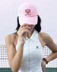 Pink tennis cap with embroidered logo and adjustable ribbon on the back strap.